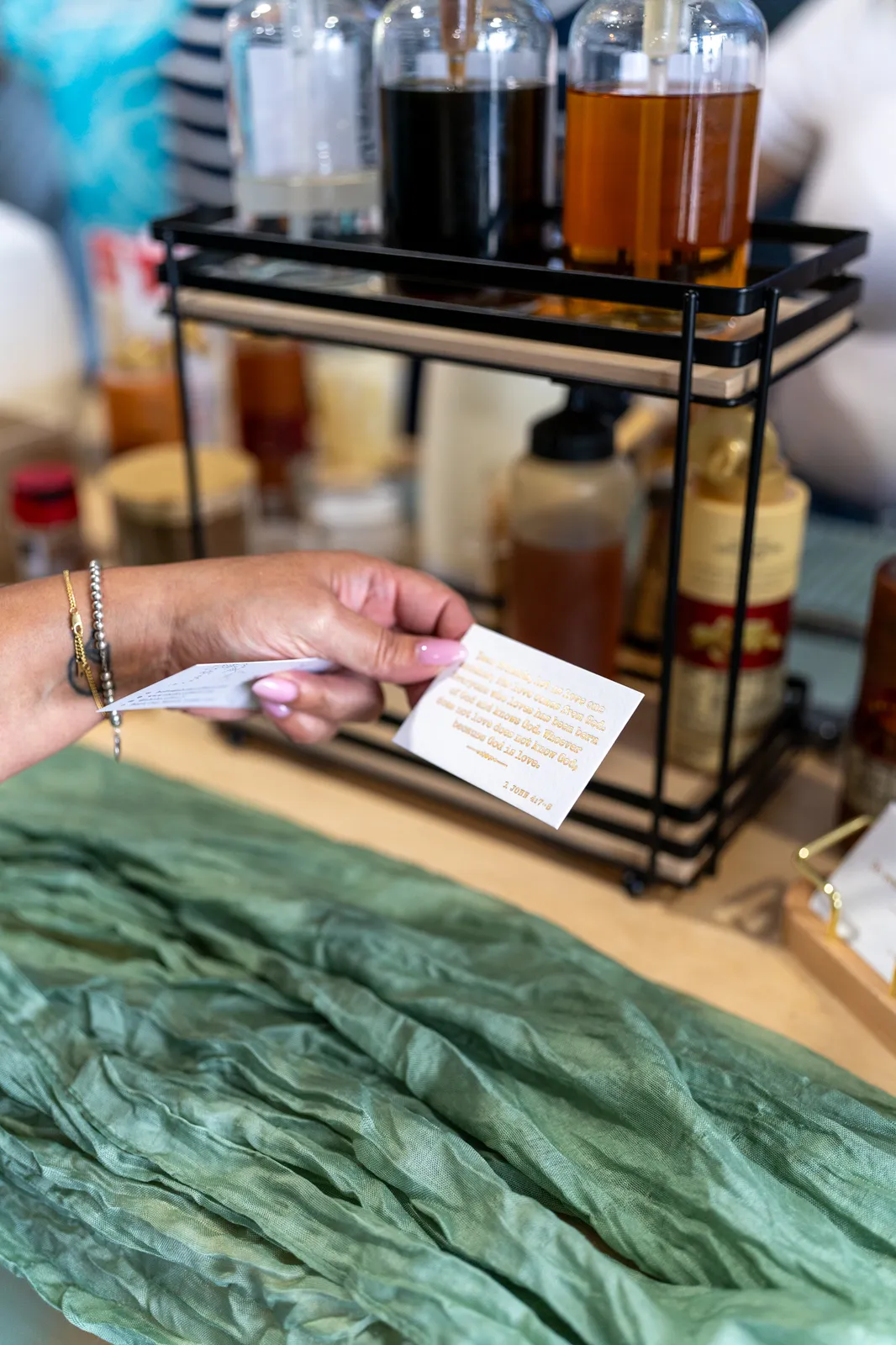 A guest holds a menu card beside the syrup rack and sage-green table runner.