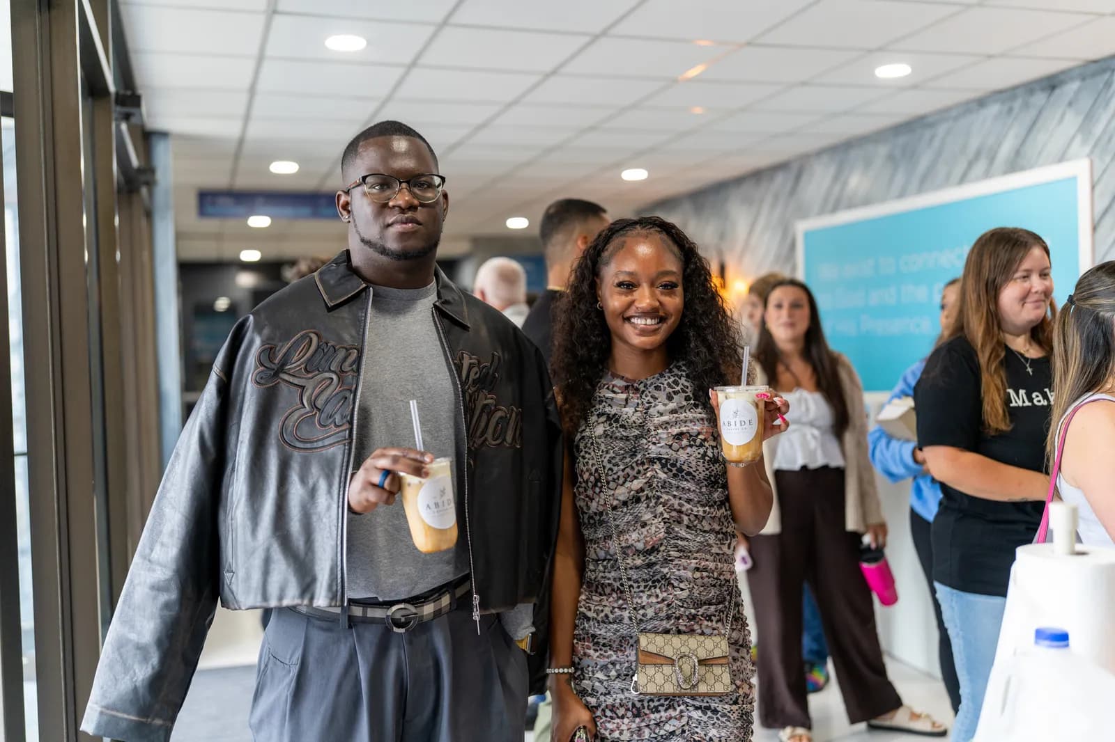 A couple poses with their iced drinks in the busy lobby.