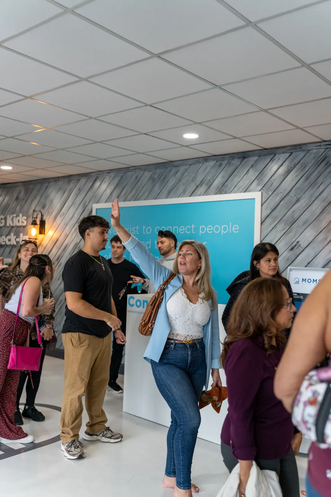 A guest waves across the lobby as the crowd mingles.