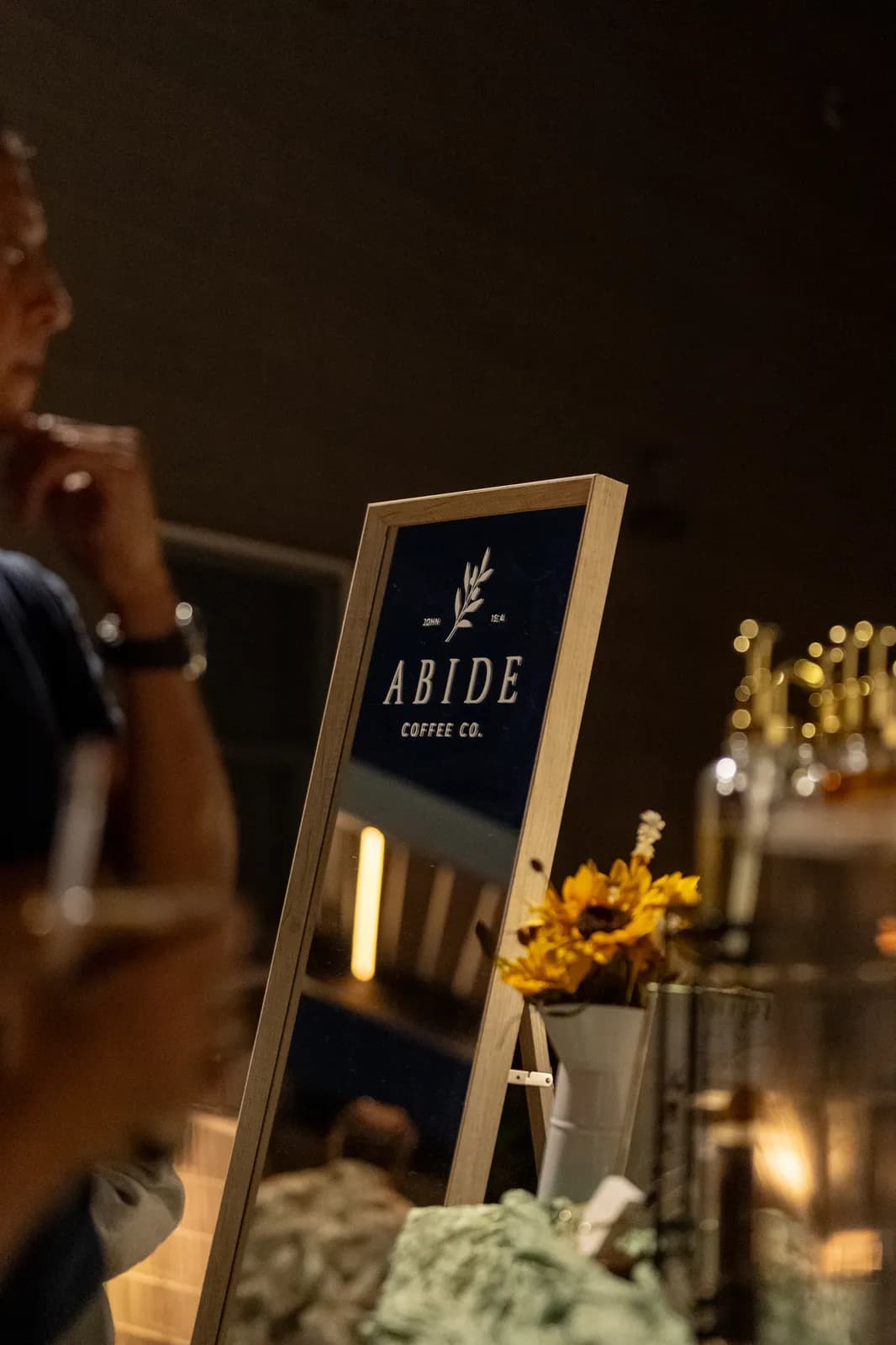 The Abide easel sign catches lantern light as service continues into the evening.